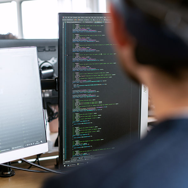 man looking at code displayed on monitor